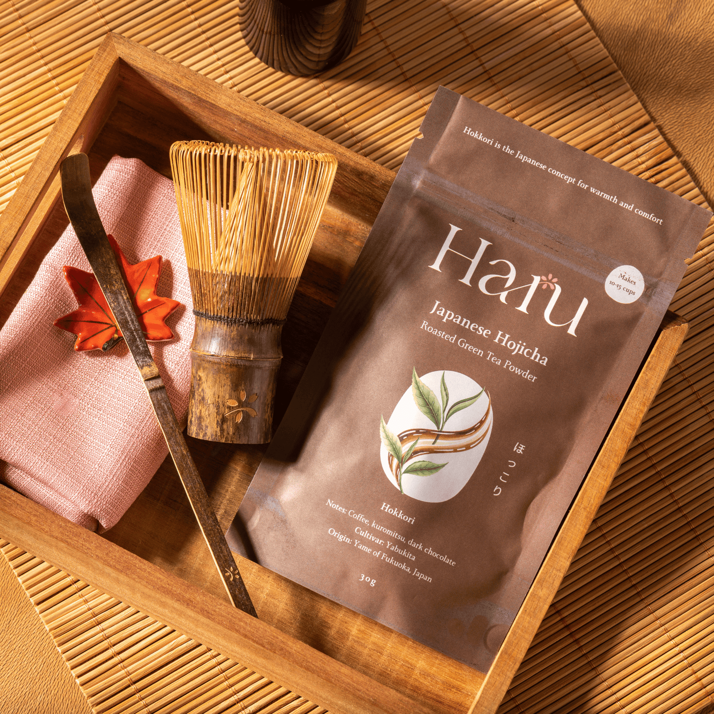 Haru Japanese Hojicha tea package with whisk and cloth on a wooden tray