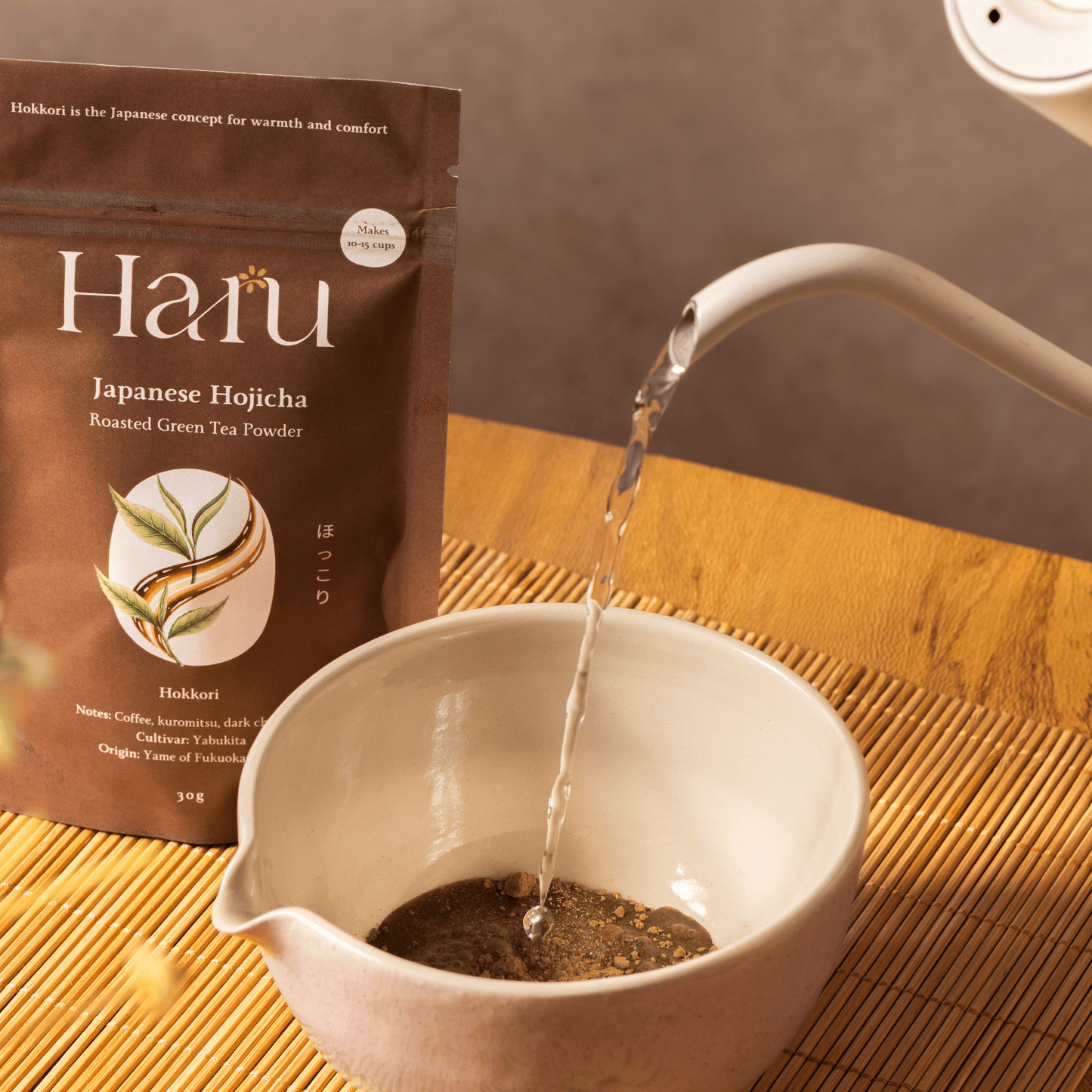Haru Japanese Hojicha green tea powder being poured into a teacup on a wooden surface.