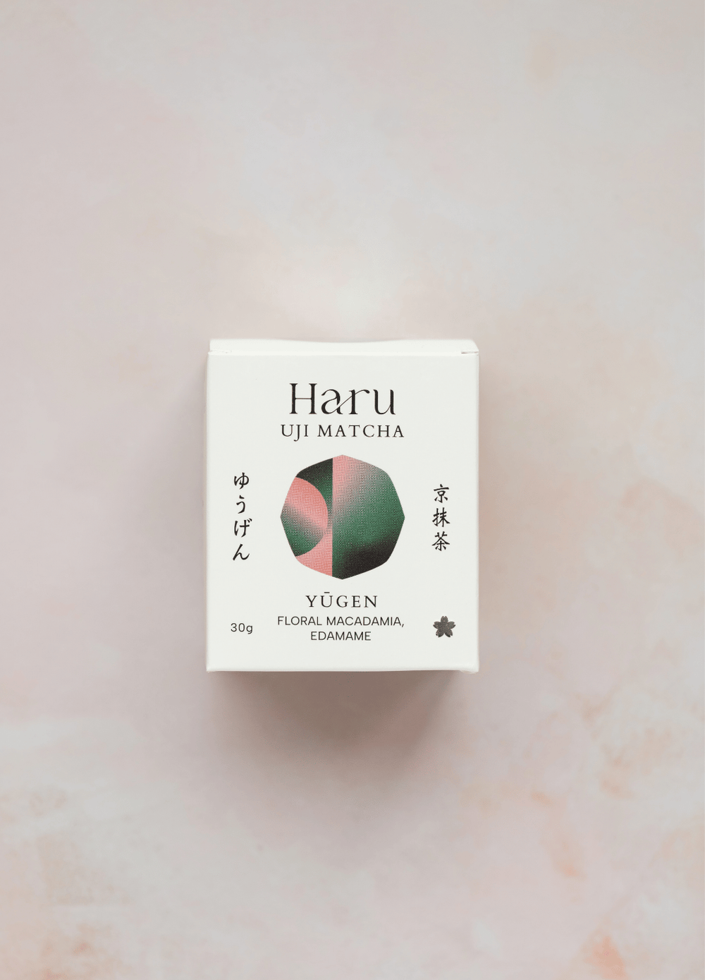 A 30g box of Haru Uji Matcha Yugen (Floral Macadamia, Edamame) on a light pink marble background. The packaging is white with black text and a central circular graphic showing pink, green, and dark green segments.