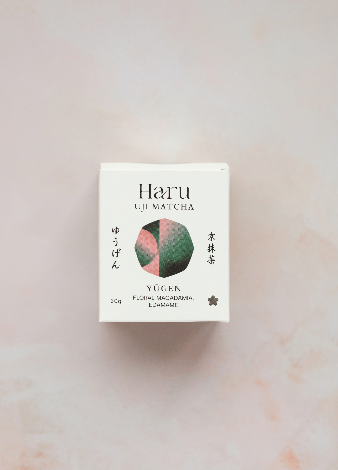 A 30g box of Haru Uji Matcha Yugen (Floral Macadamia, Edamame) on a light pink marble background. The packaging is white with black text and a central circular graphic showing pink, green, and dark green segments.